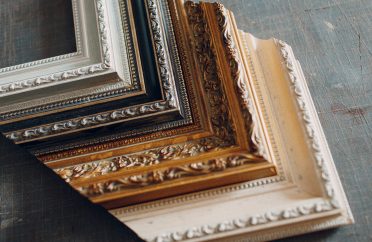 Vase with ears of wheat and photo frames against brick wall, close up